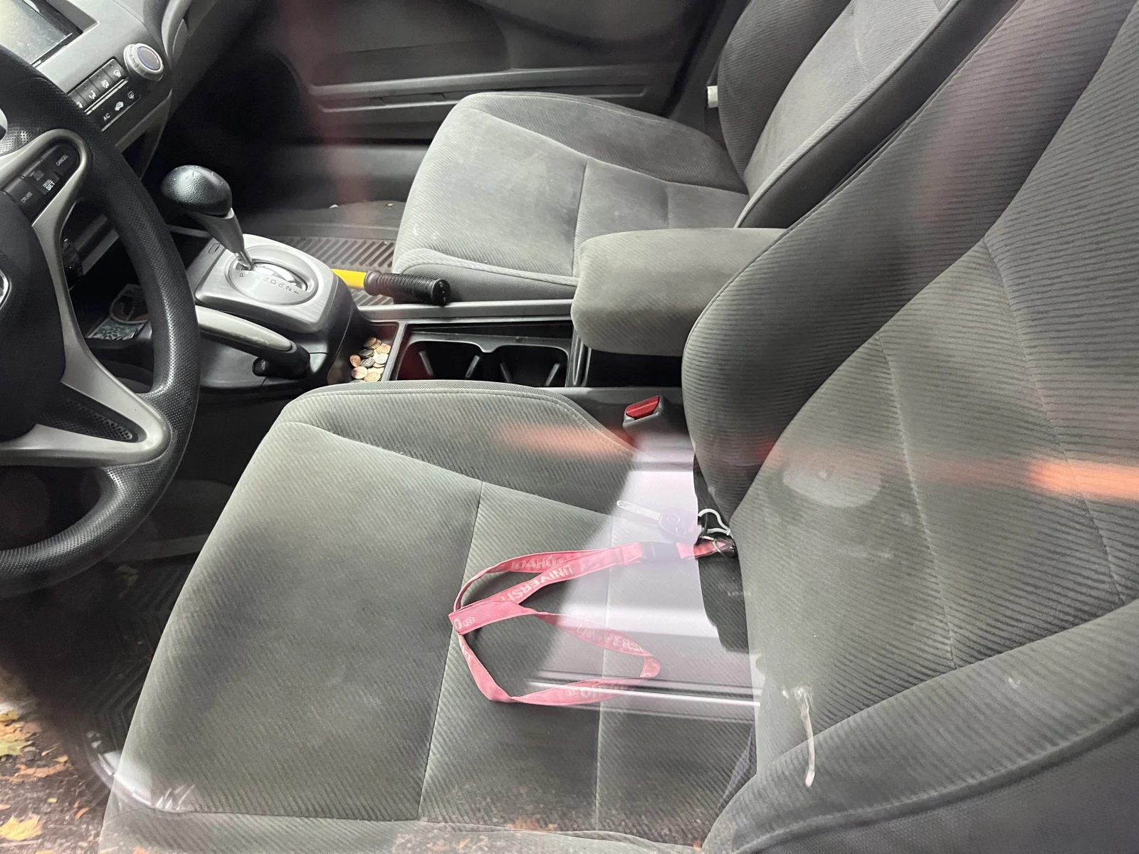 Gray cloth front seats, automatic gear selector, handbrake and a pink strap resting on the driver seat.