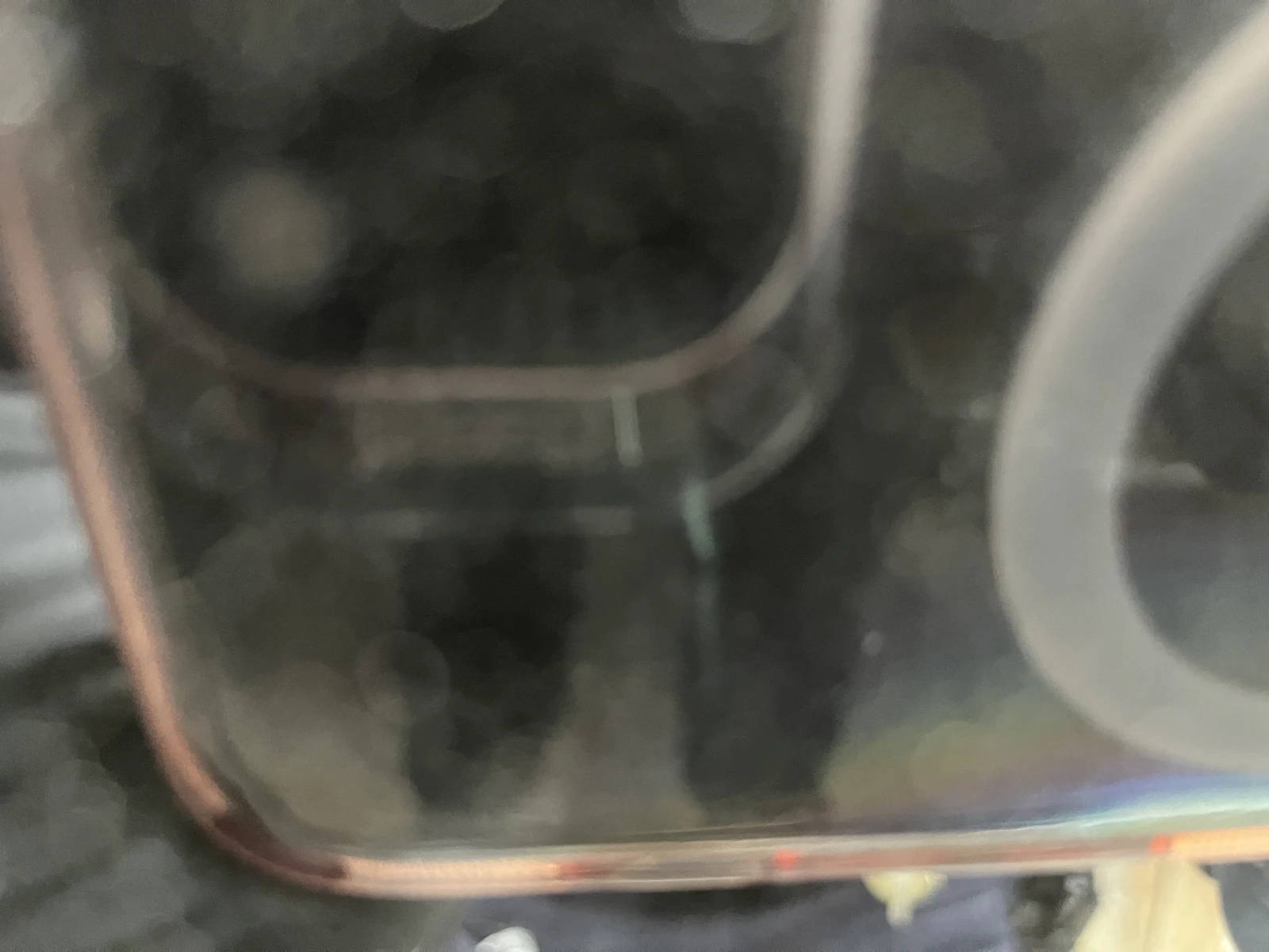 Close, soft-focus view through reflective vehicle glass of a dark rectangular object with rounded edges.