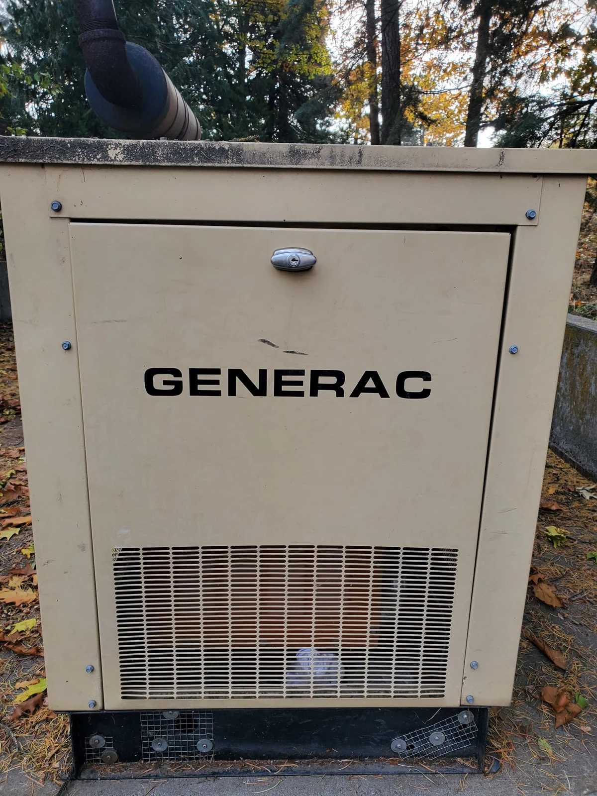 Tan outdoor generator cabinet with a Generac label and ventilation grille.