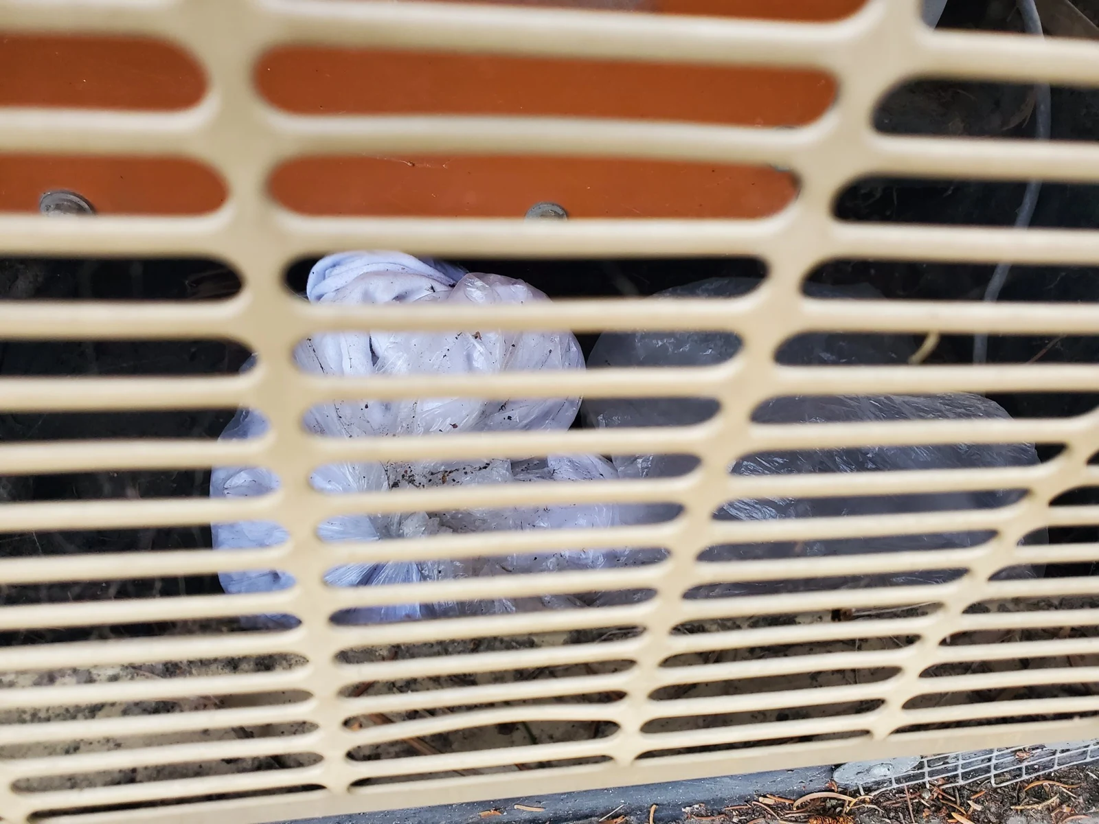 Close view through a generator ventilation grille of white material inside, with an orange component behind it.