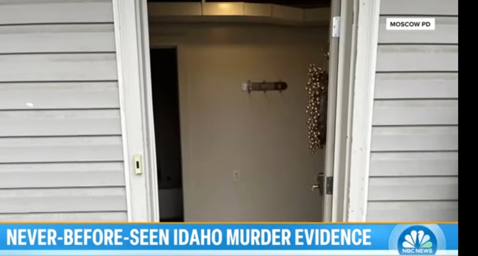 News screenshot of an open exterior doorway with pale siding, showing an interior wall and coat hooks.