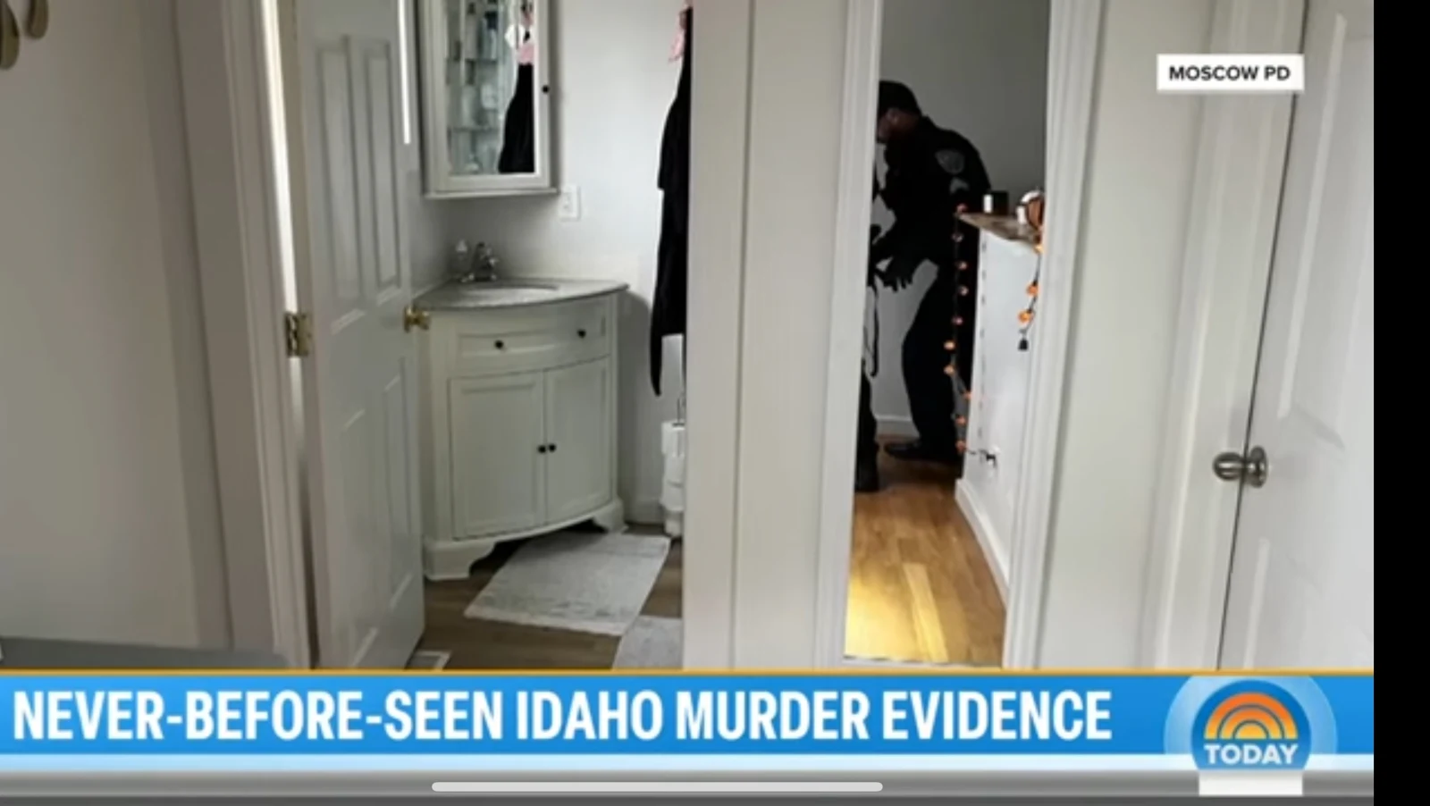News screenshot of a hallway beside a bathroom sink and mirror, with a person visible through another doorway.