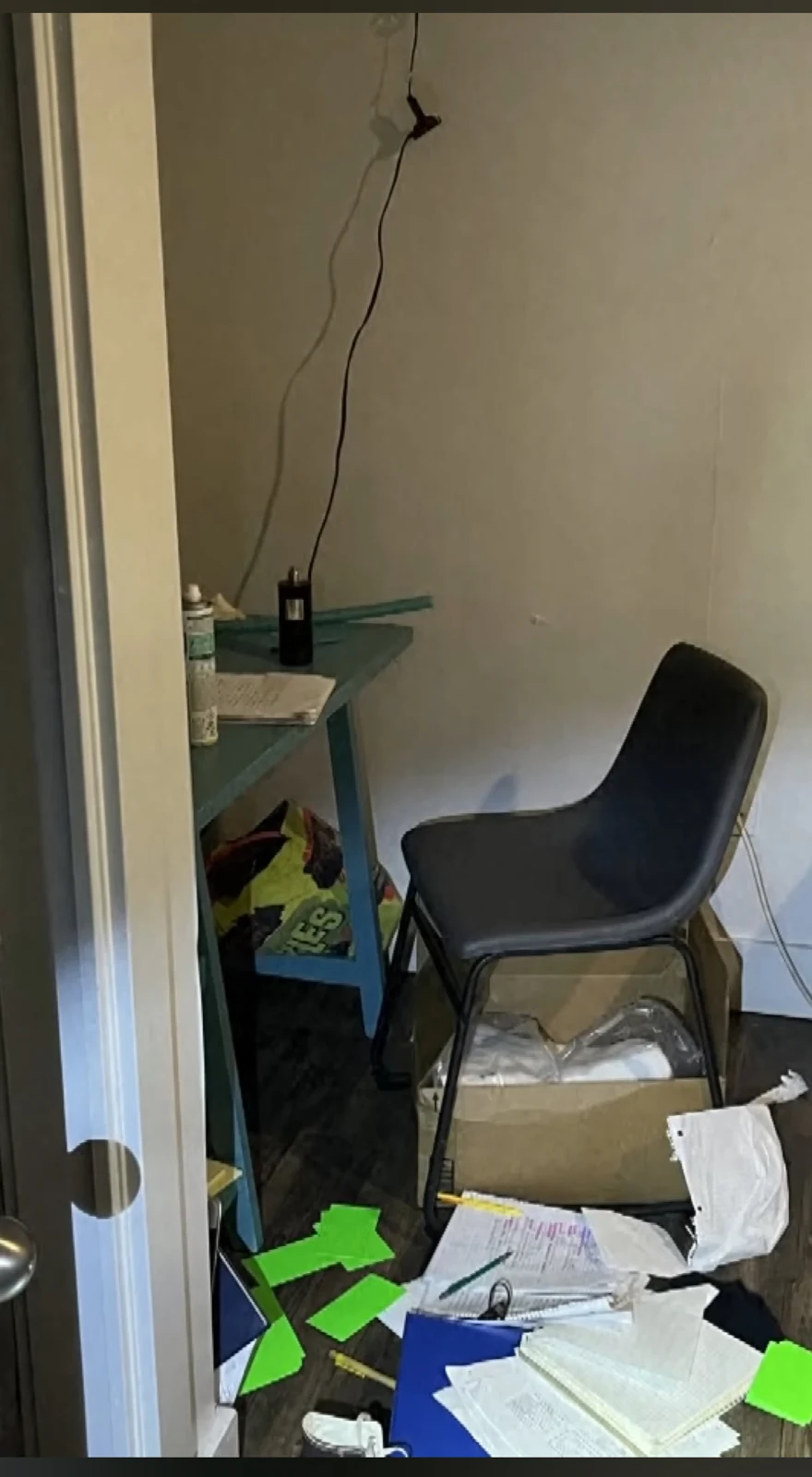 Small room with a chair, desk, hanging cable and papers scattered across the floor, including bright green cards.