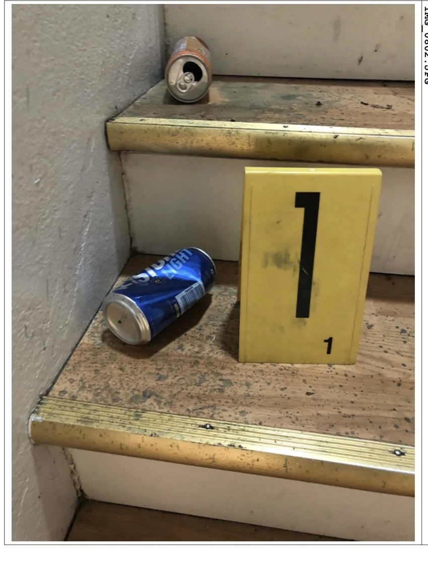 Blue beverage can on a stair beside yellow evidence marker 1, with another can above.