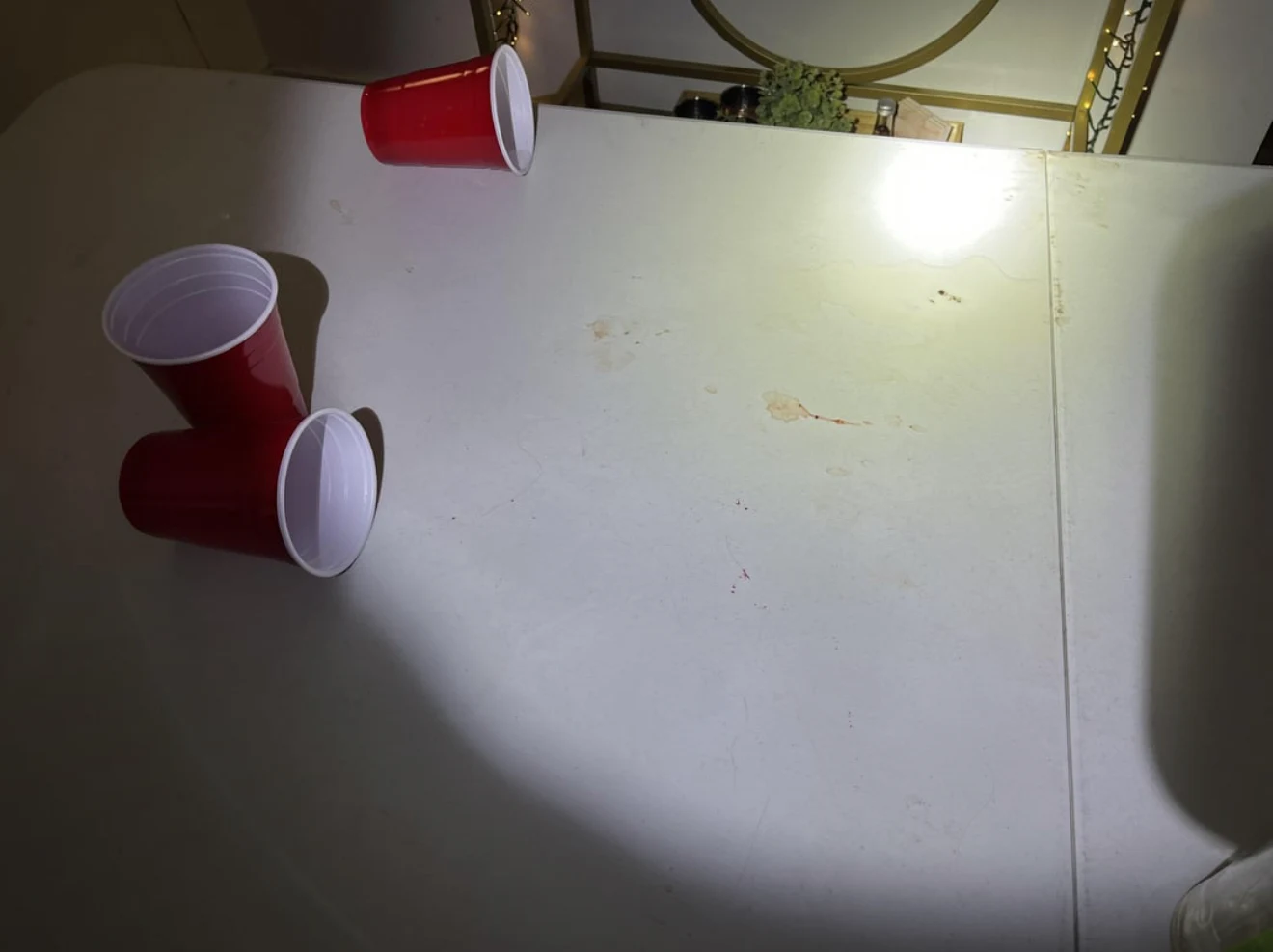 Three red plastic cups on a white folding table under a bright flashlight spot.