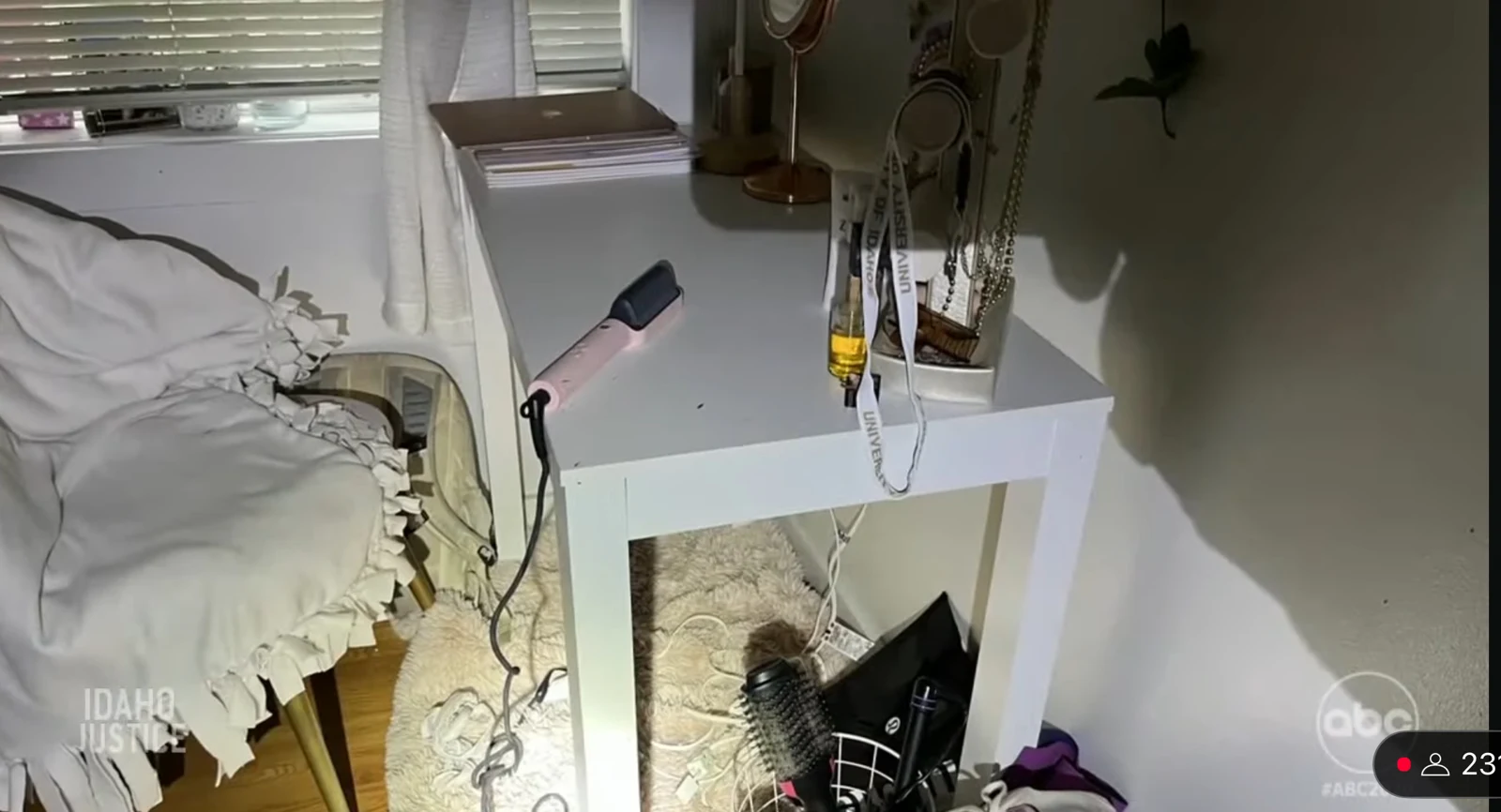 News screenshot of a white bedside table with jewelry, cords and a hair-styling tool beside white bedding.