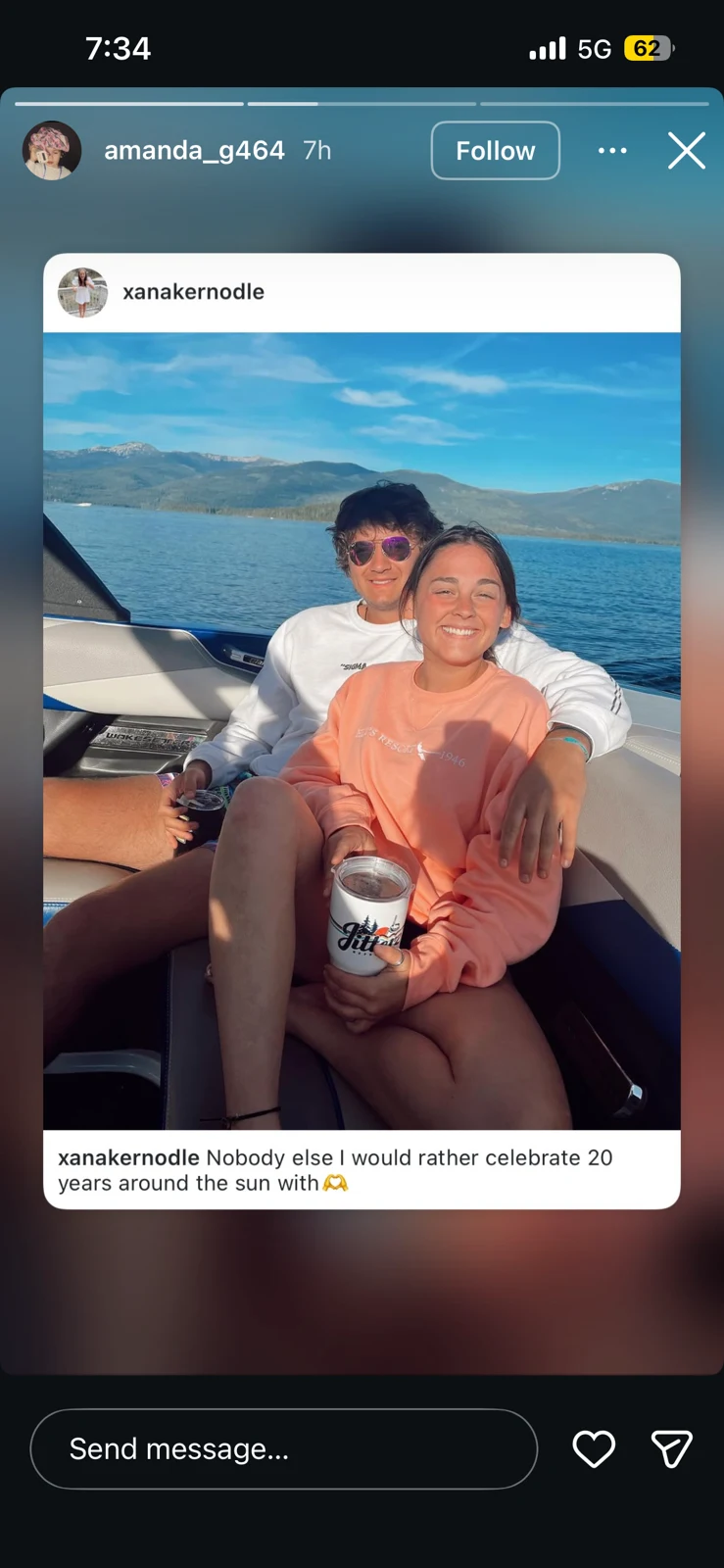 Social-media story sharing a photograph of two people seated on a boat against blue water and mountains.