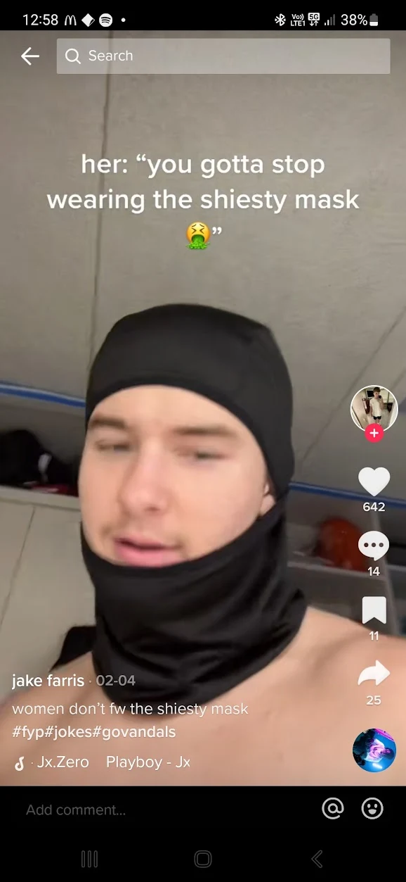 Short-video screenshot of a person wearing a black head covering and lowered face covering beneath an on-screen joke about masks.