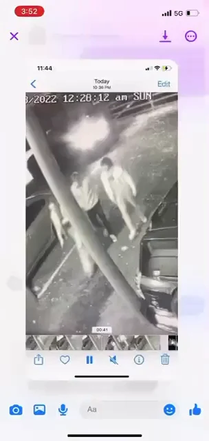 Phone video-viewer screenshot showing a black-and-white security-camera image of a person beside a vehicle, with a timestamp overlay.