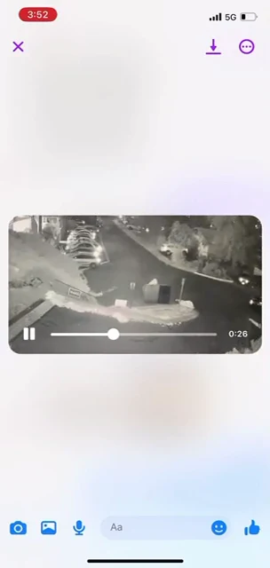 Phone video-viewer screenshot of an overhead nighttime parking area with parked cars and bins; playback shows 0:26 remaining.