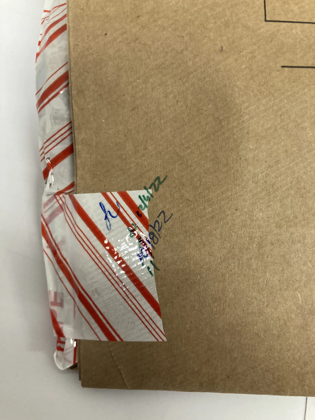 Close view of the corner of a brown evidence envelope sealed with red-striped tape and handwriting.
