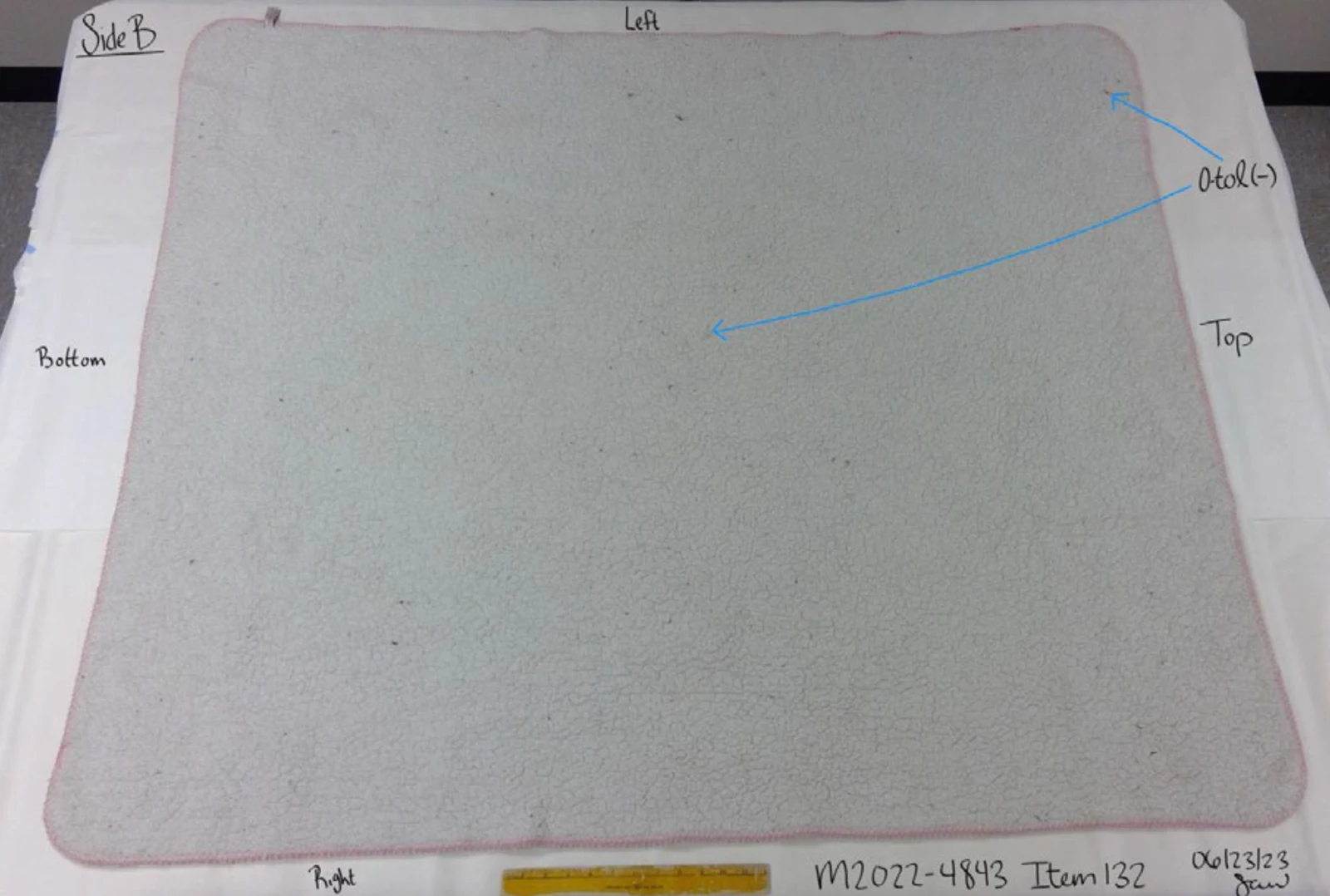 Plain gray reverse side of a rectangular mat with pink edging, blue arrows and handwritten testing annotations.
