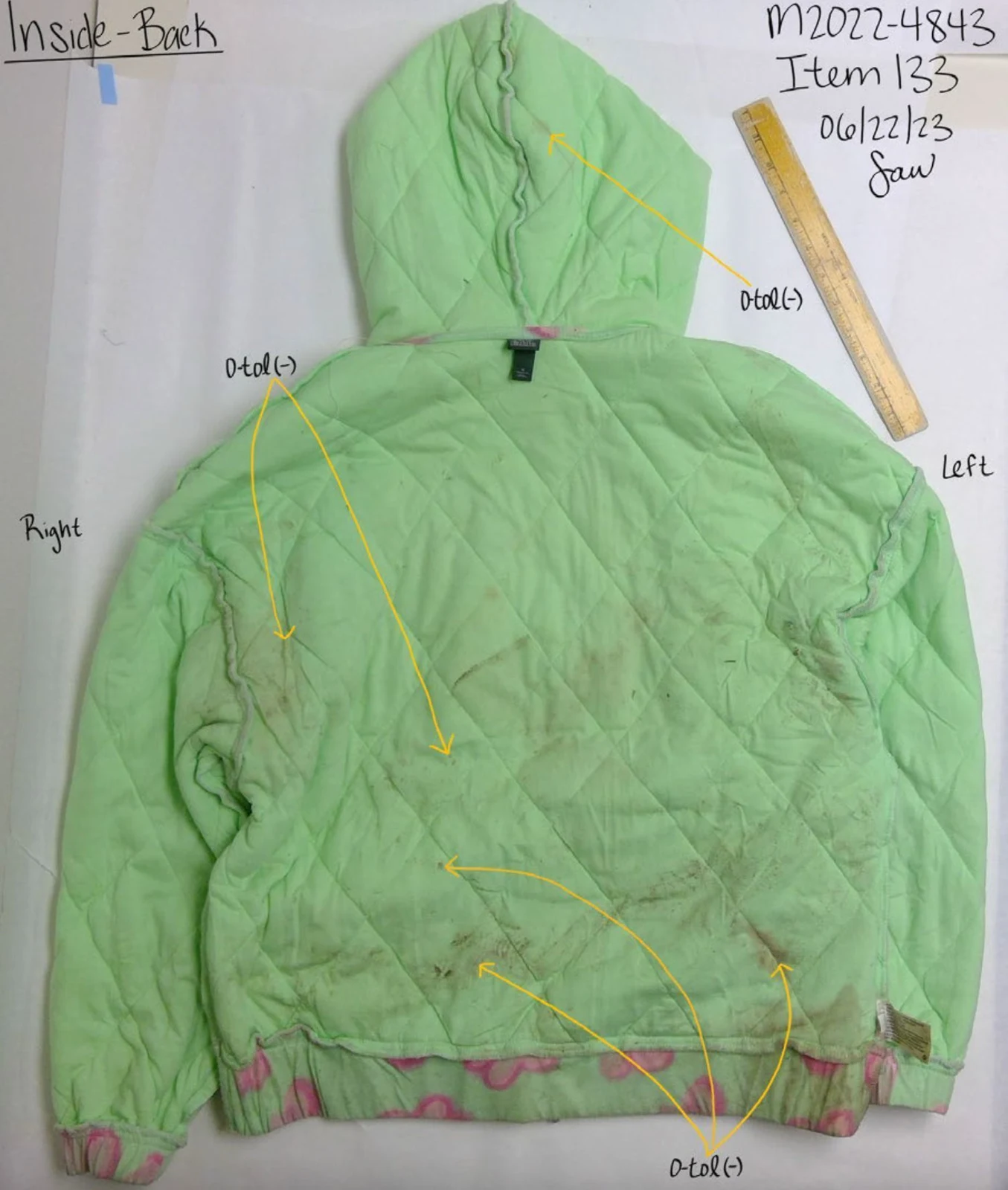 Inside back of a green quilted hooded jacket with yellow arrows and handwritten testing notes.