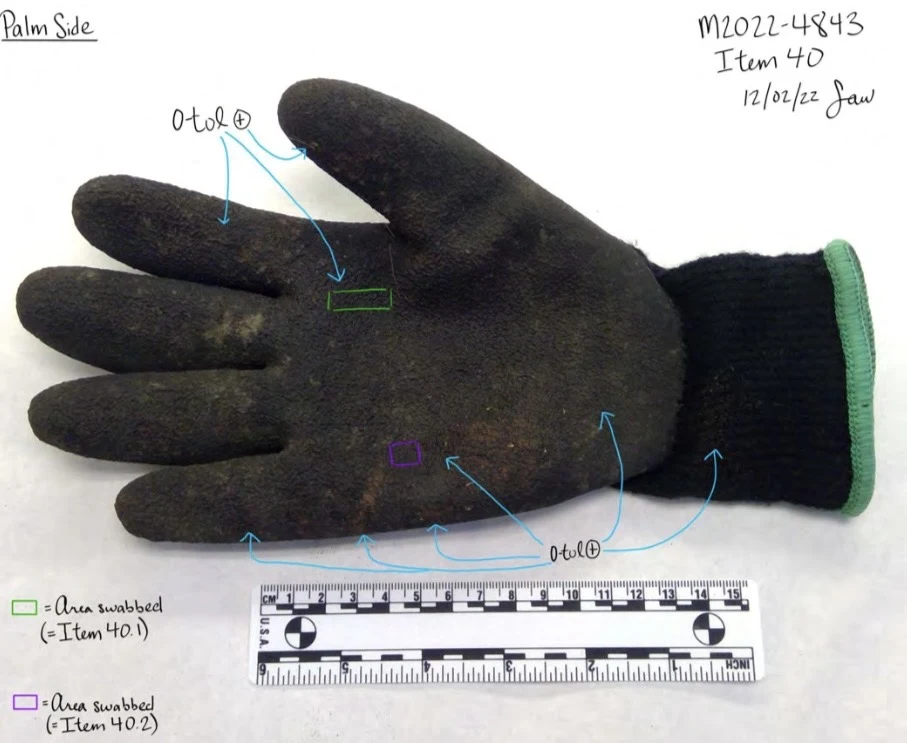 Palm of a black work glove with green cuff, visible discoloration, a measurement scale and colored testing annotations.