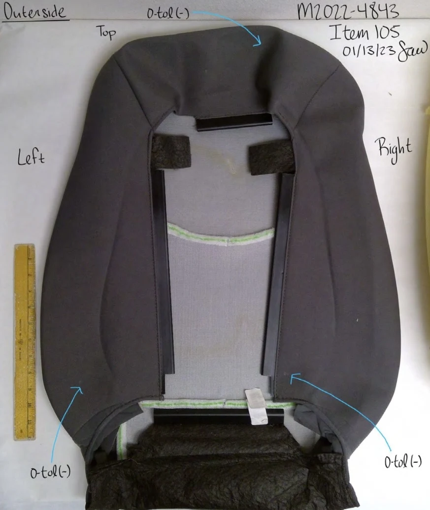 Back exterior of a removed dark seat cover with a central opening and gray backing visible, beside a ruler and blue arrows.