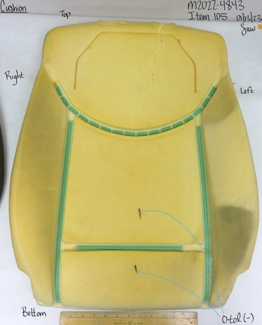Yellow foam seat-back cushion with green attachment strips, small cuts and blue testing arrows.