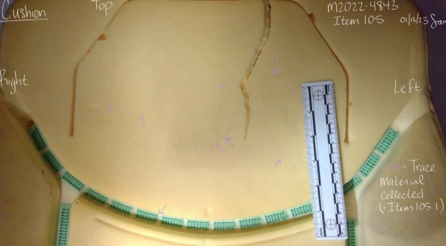 Close photograph of yellow seat foam with a curved green strip and a measurement scale, with trace-material collection annotations.