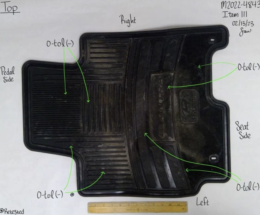 Black Hyundai rubber floor mat with ridges and visible dirt, beside a ruler with pedal-side and seat-side annotations.