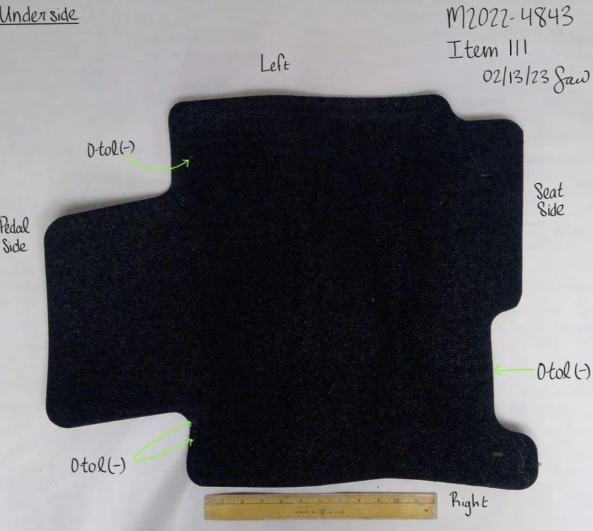 Black textured underside of a shaped vehicle floor mat beside a yellow ruler, with handwritten orientation labels and green testing arrows.