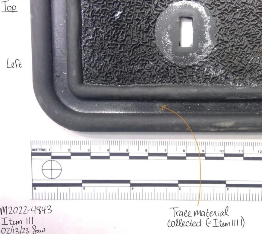 Close view of a rubber floor-mat corner and fastening slot beside a measurement scale, with a trace-material collection arrow.
