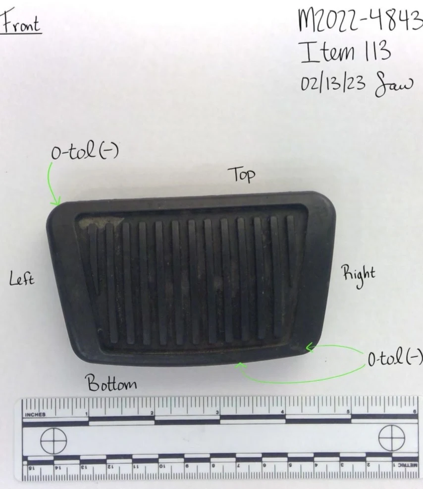 Front of a black ridged rectangular vehicle pedal pad above a measurement scale, with top and bottom labels.