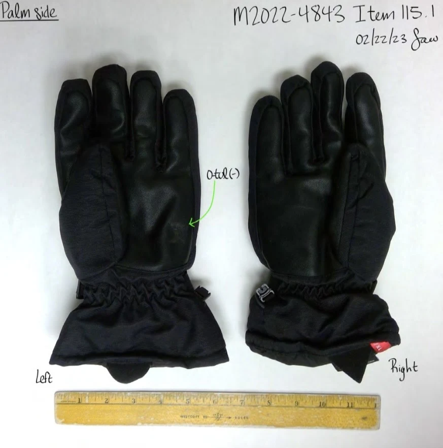 Palm sides of a pair of black winter gloves with smooth palms and gathered cuffs, beside a yellow ruler.