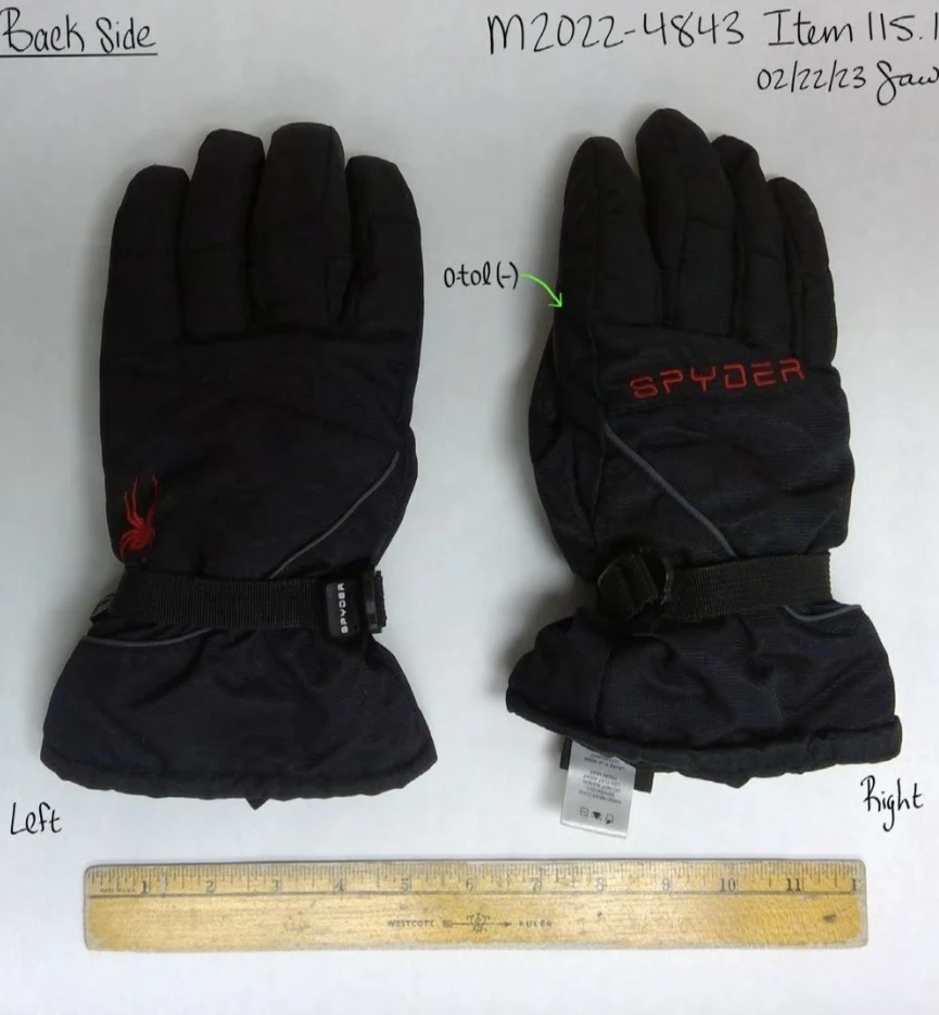 Backs of black Spyder winter gloves with wrist straps, red lettering and a yellow ruler below.