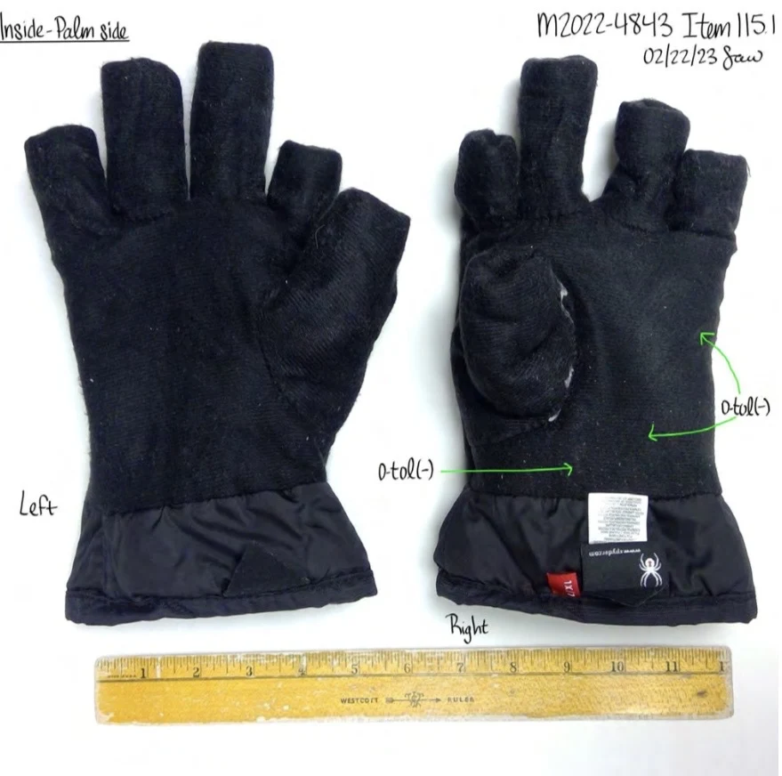 Palm sides of two black glove linings turned inside out, with tags, cut or shortened finger sections and a ruler.