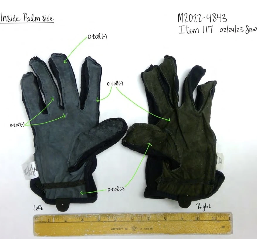 Inside palm surfaces of two gloves turned inside out, one gray and one dark, with exposed seams and a ruler below.