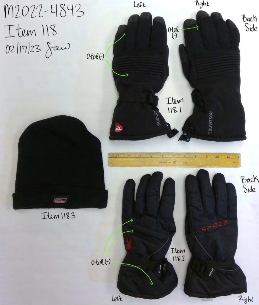 Two pairs of black winter gloves and a black knit cap arranged on white paper, with a ruler and handwritten item labels.