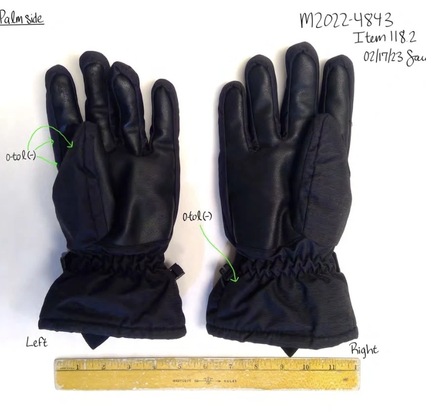 Palm sides of black winter gloves with smooth palms and gathered cuffs, with green arrows and a ruler.