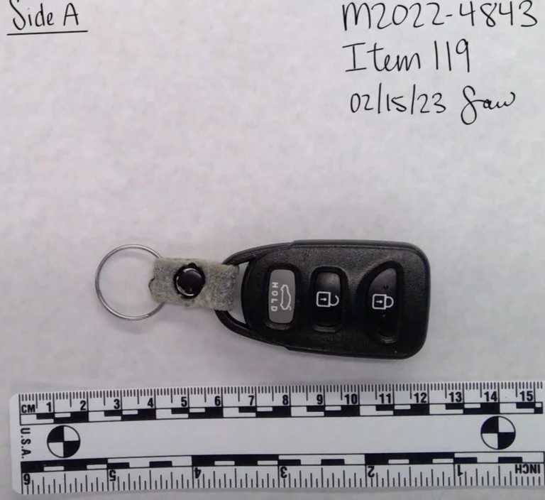 Front of a black vehicle key fob on a metal ring, showing lock, unlock and hold buttons above a measurement scale.