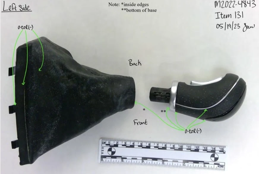 Left-side view of a detached gear-shift knob and black flexible boot, with green testing arrows and a measurement scale.