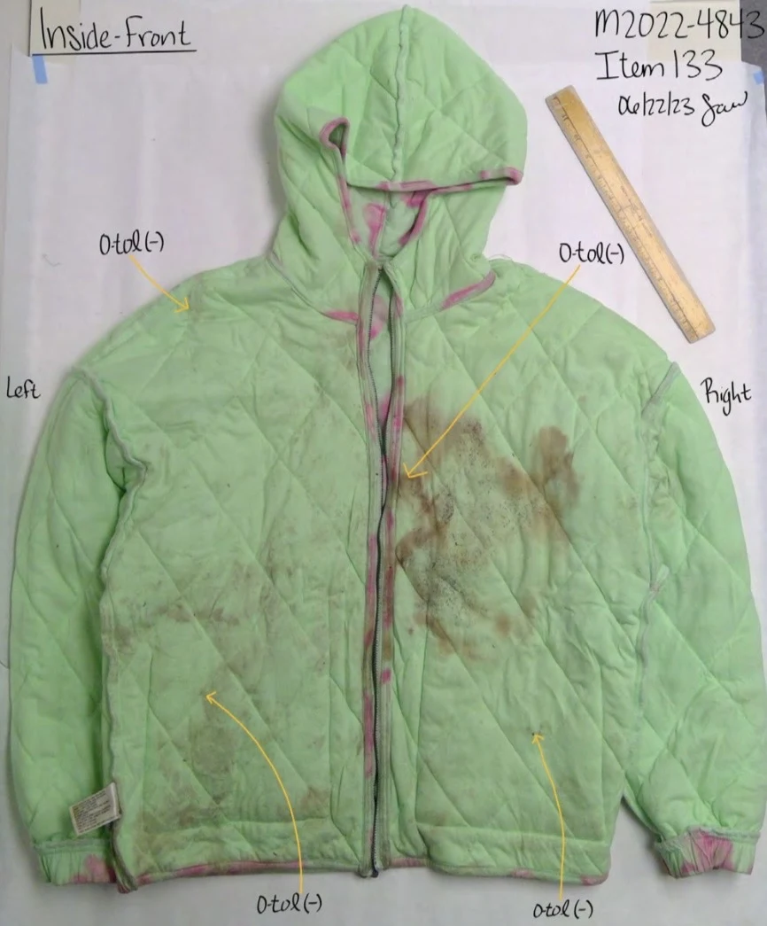 Inside front of a green quilted hooded jacket with brown discoloration, a yellow ruler and test-area annotations.