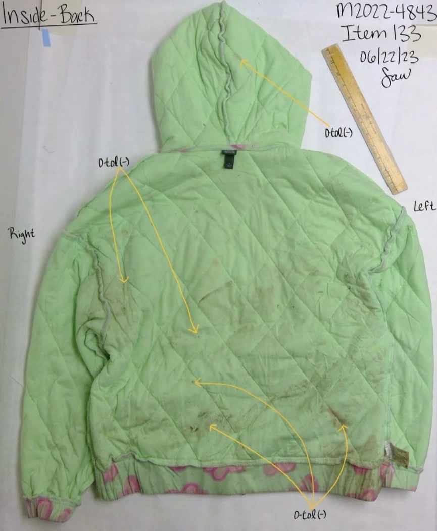 Inside back of a green quilted hooded jacket, with arrows and a ruler beside the hood.