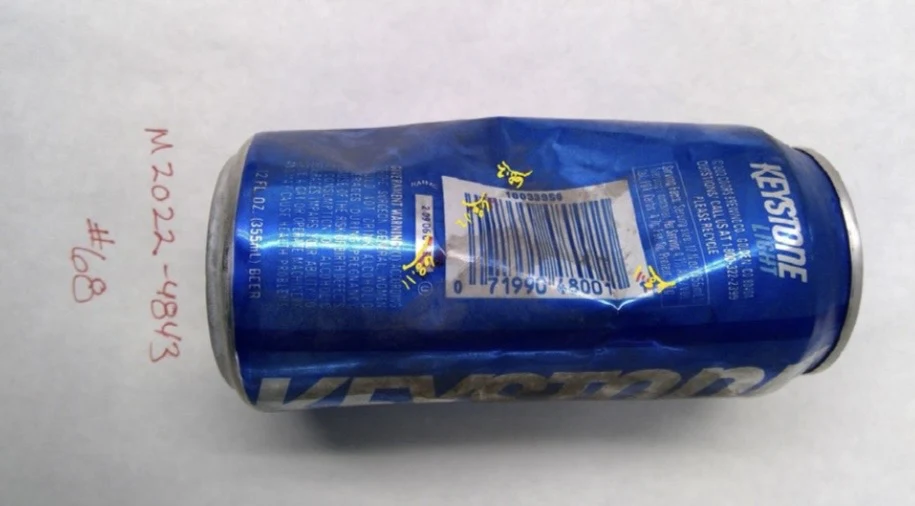 Barcode side of a blue Keystone can with yellow handwritten sample marks, labeled item 68.