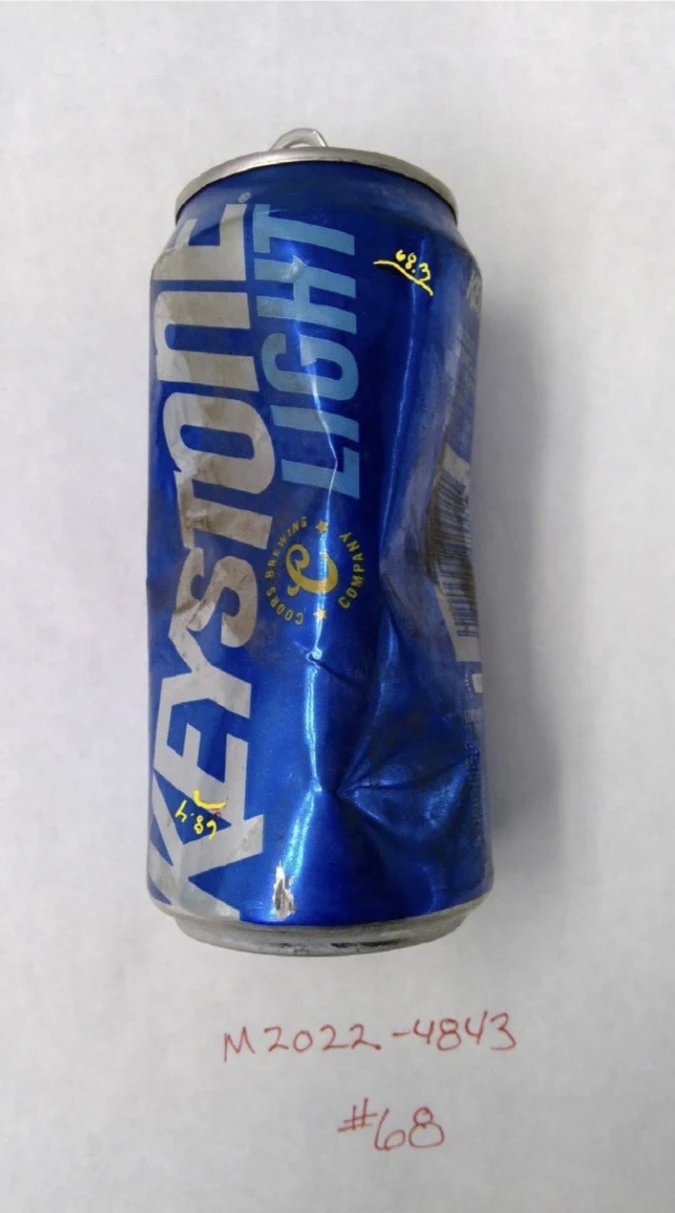 Vertical view of a dented blue Keystone Light can with yellow handwritten marks, labeled item 68.