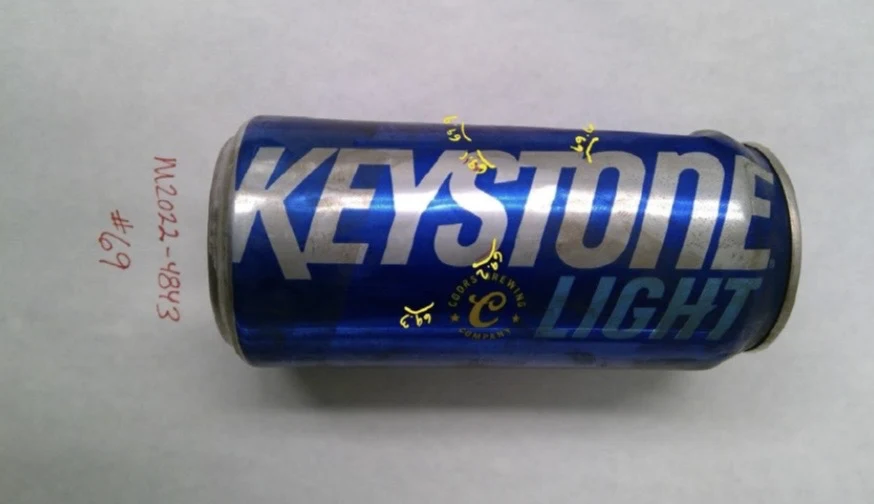 Side view of a blue Keystone Light can with yellow handwritten sample marks across the printed lettering, labeled item 69.