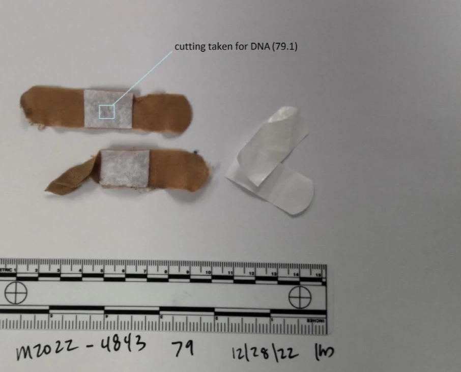 Two tan adhesive bandages and a pale backing piece above a measurement scale, with an outlined area labeled as a cutting taken for DNA.