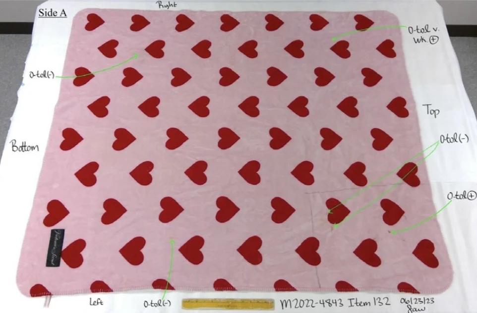 Pink mat covered in red hearts, beside a yellow ruler with handwritten orientation labels and green testing arrows.