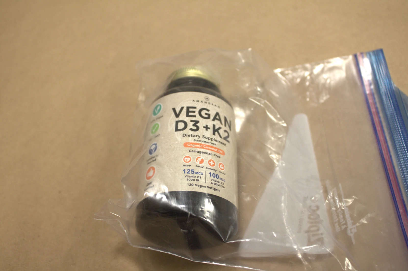 Angled photograph of a Vegan D3+K2 supplement bottle inside a clear resealable bag with a white paper insert.
