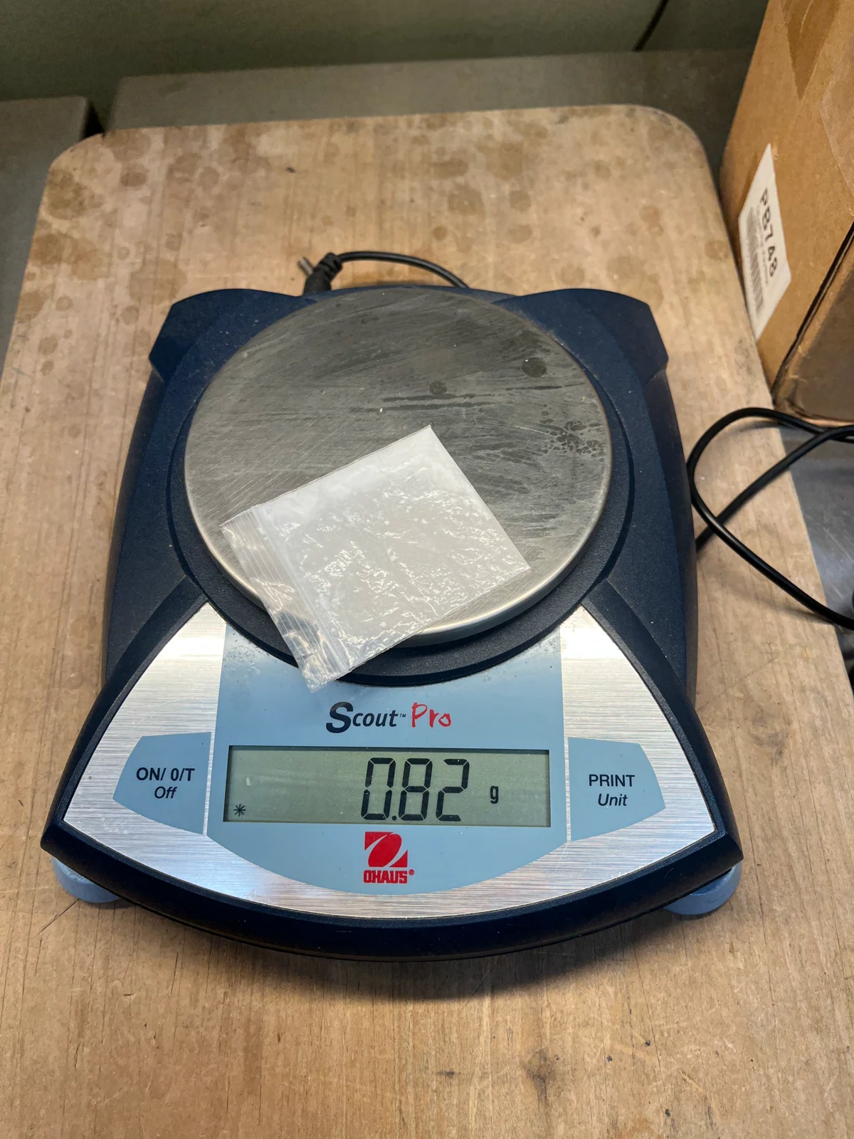 Small clear bag with pale material on a Scout Pro digital scale displaying 0.82 g, on a wooden tabletop.