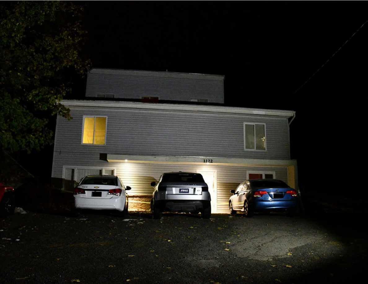 House exterior at night with three parked cars and illuminated windows.