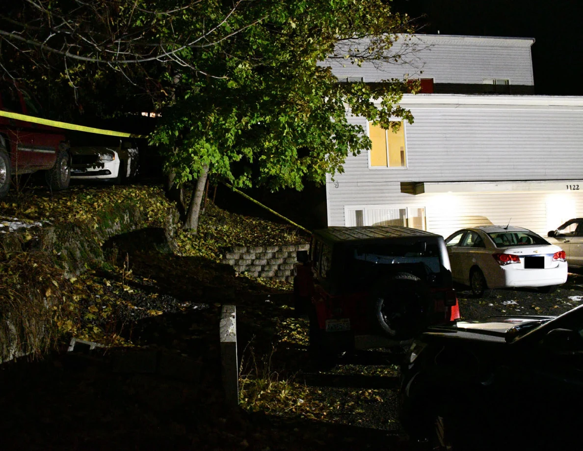 House exterior, parked vehicles, trees and yellow barrier tape.