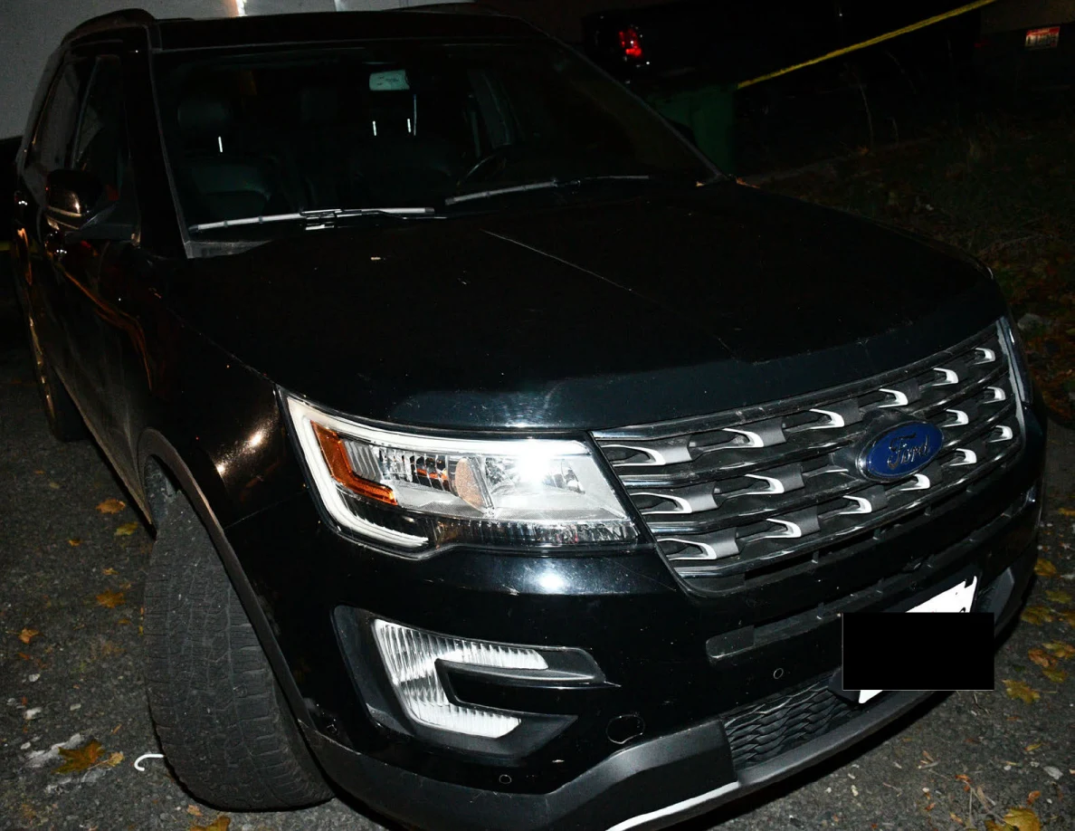 Front of a black SUV with a redacted license plate.
