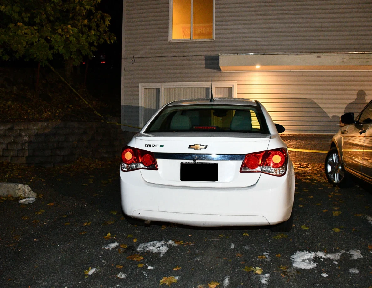 Rear of a white Chevrolet sedan parked outside a house.