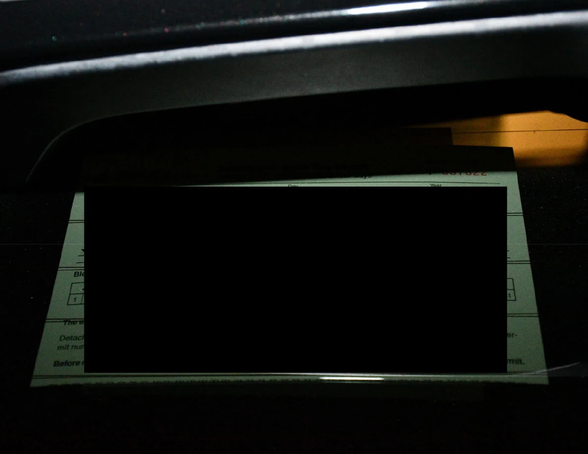 Vehicle window with a largely redacted paper notice.