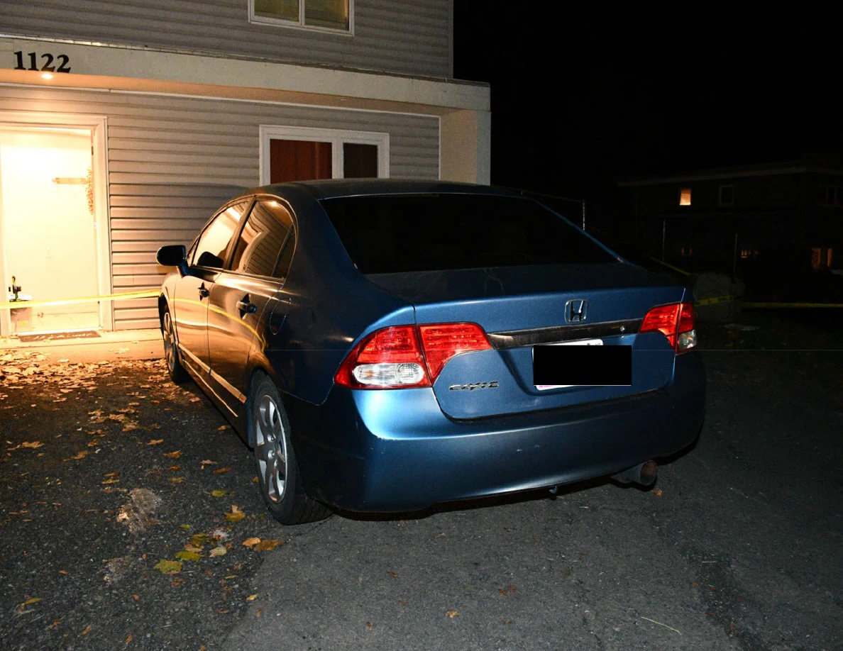Rear of a blue Honda sedan outside a house.