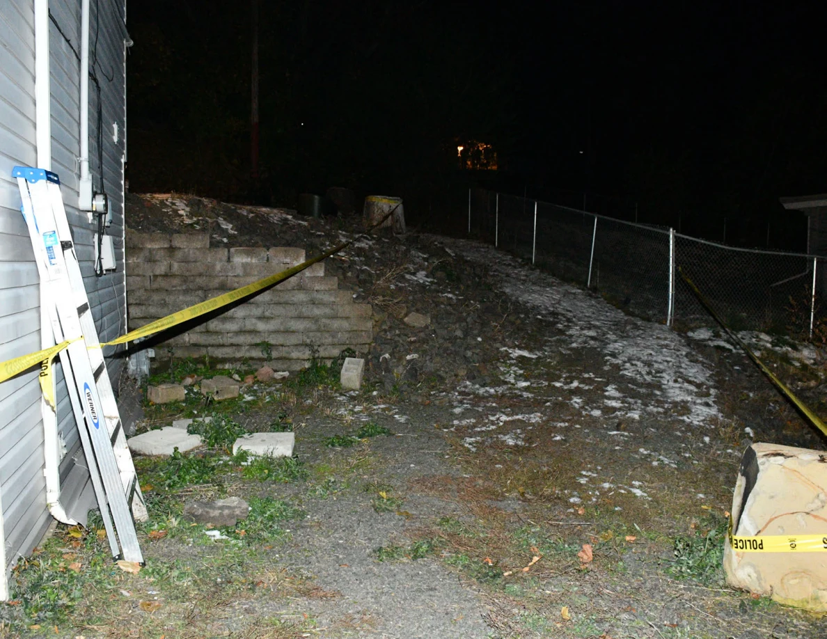 House side wall, ladder, retaining wall, fence and yellow barrier tape.