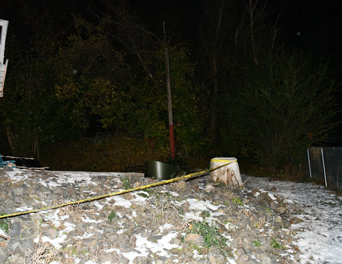 Snow-covered slope, tree stump, trees and yellow barrier tape.